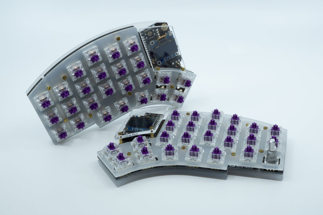 A front photo of a Kyria in a frosted plate case with one half on its side, showing clear OLED windows.