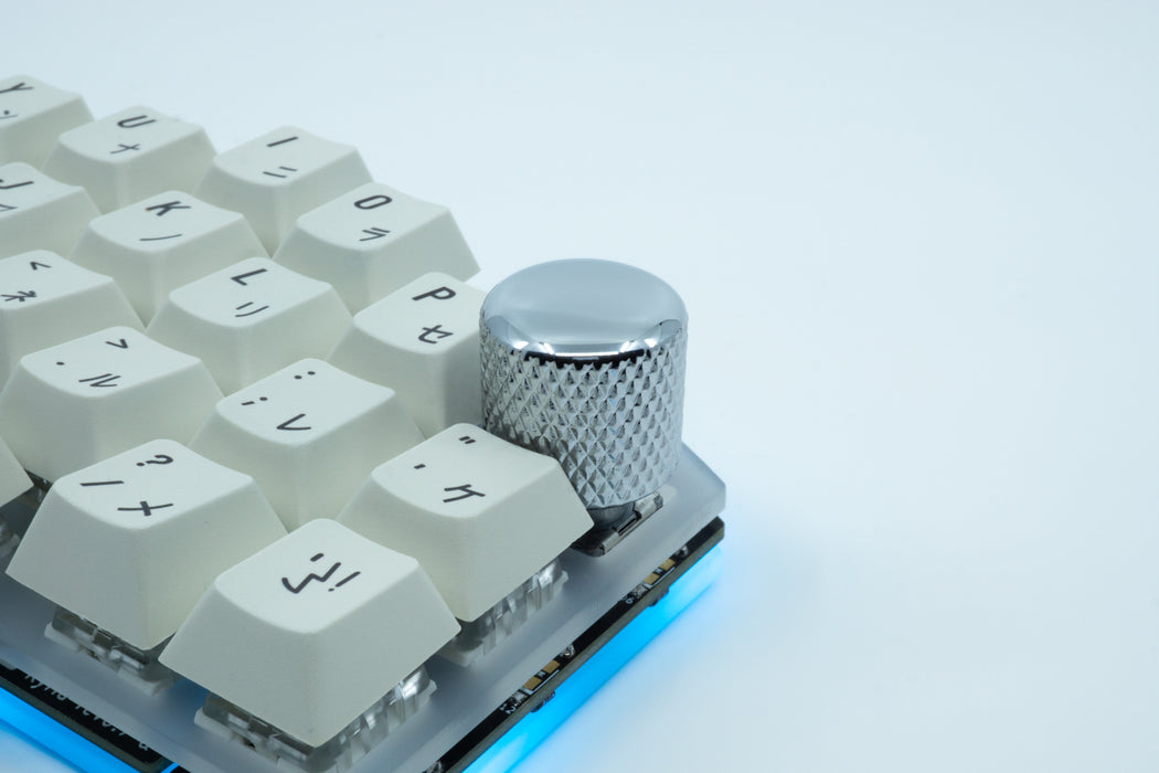 A photo showing a shiny knurled metal encoder knob on the top right column on a Kyria.